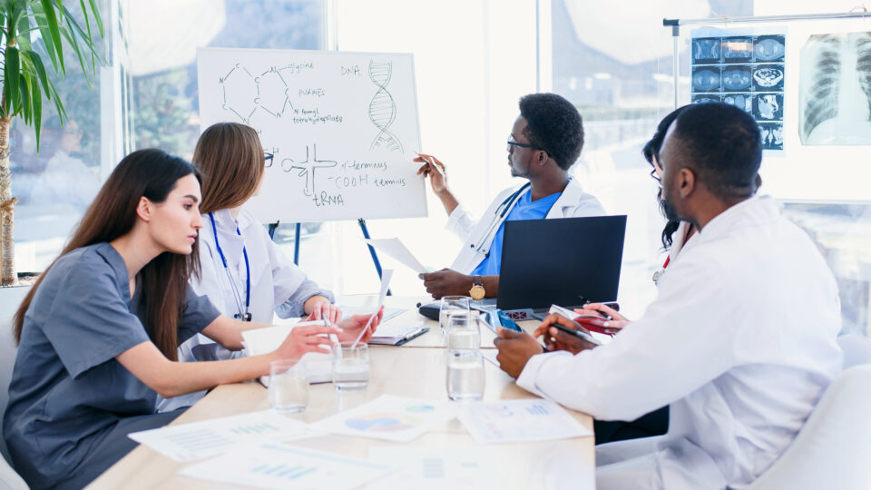 Group of international doctors or interns with mentor have a meeting and making notes at hospital room. Health care concept. Doctors discuss the patient's diagnosis at meeting room.